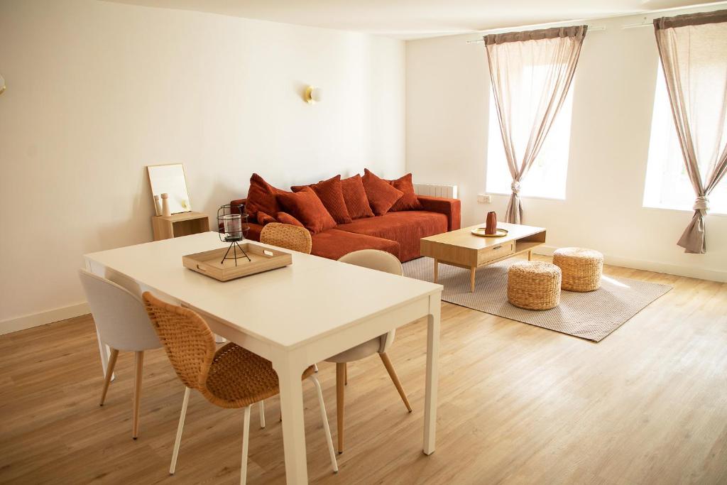 a living room with a white table and a couch at Le Rozé - Appart'Escale in Saint-Nazaire