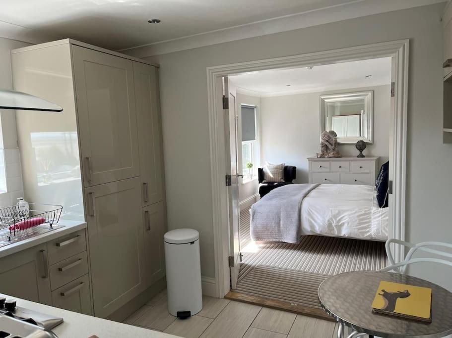 a white bedroom with a bed and a bathroom at Beautiful Seafront Studio Apartment in Cleethorpes