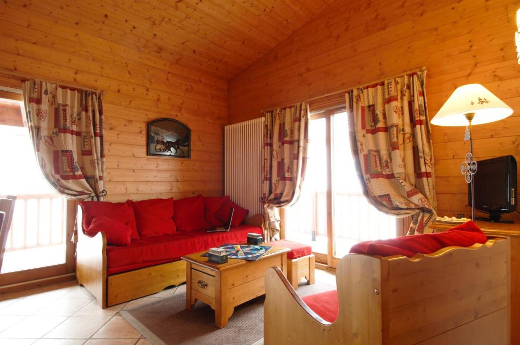 a living room with a red couch and a table at Résidence Pierre &amp; Vacances Premium Les Alpages de Chantel in Arc 1800