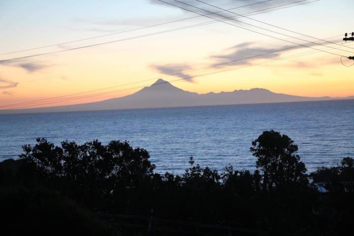 Seaview Cottage في Mokau: اطلالة على جبل في المحيط وقت الغروب