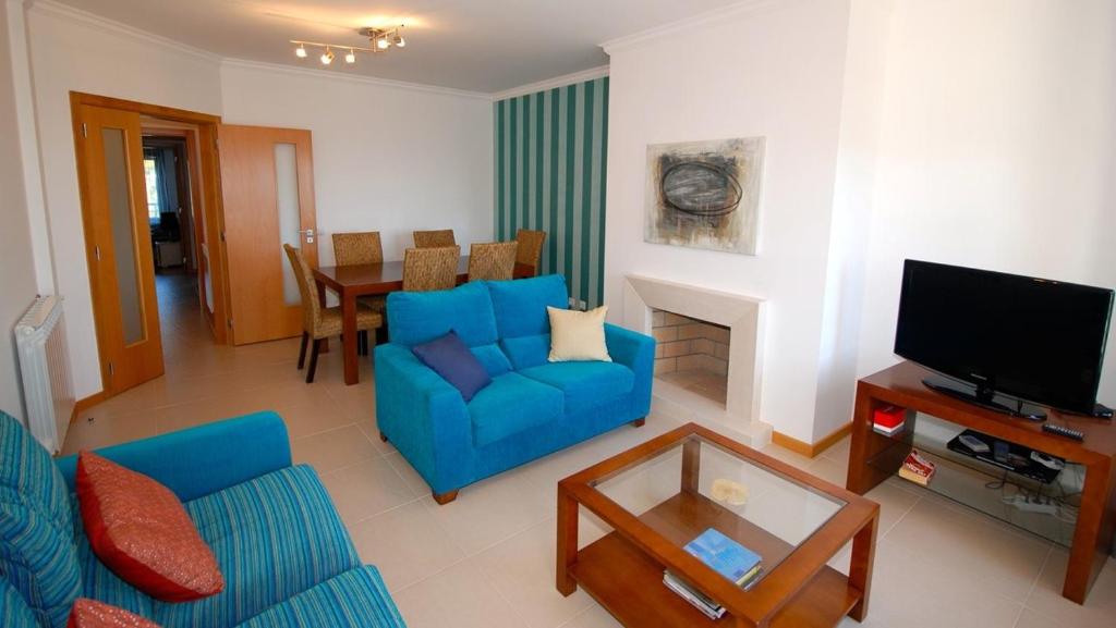 a living room with a blue couch and a tv at Alojamento Turistico in Maceira