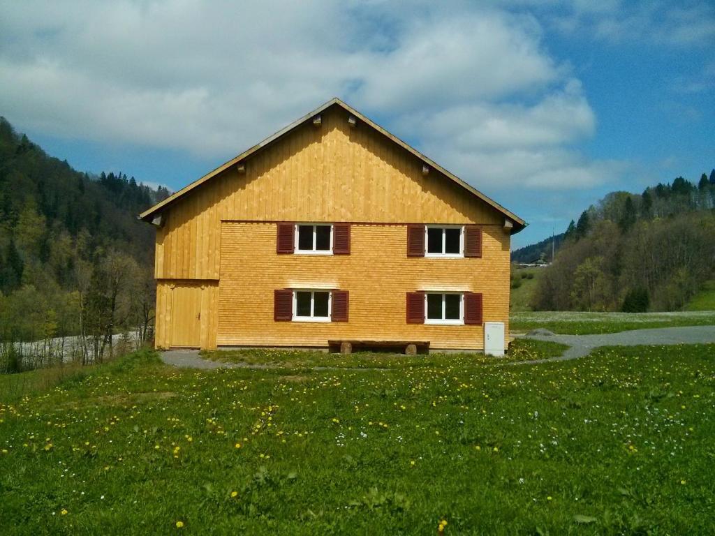 ein großes Holzhaus auf einem Grasfeld in der Unterkunft Löchle. Ferienhütte im Bregenzerwald, Andelsbuch in Andelsbuch