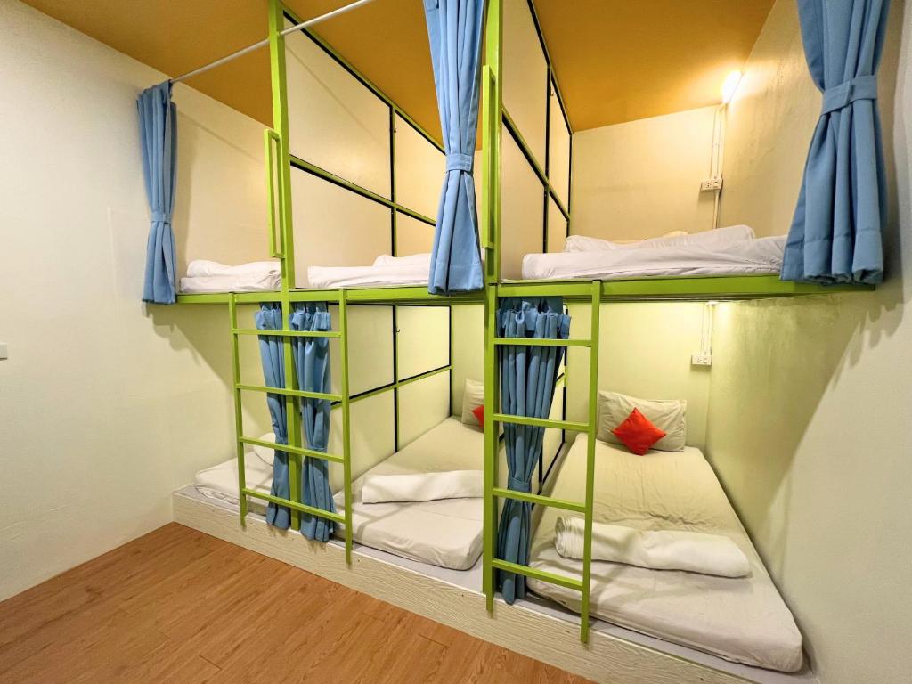 a room with three bunk beds in a hostel at Sleepy Station Hostel in Kata Beach
