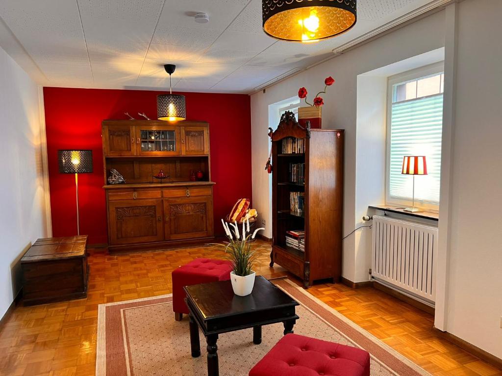 a living room with red walls and a table and a chair at Froilein Sophie - Wlan, Küche, TV in Malterdingen