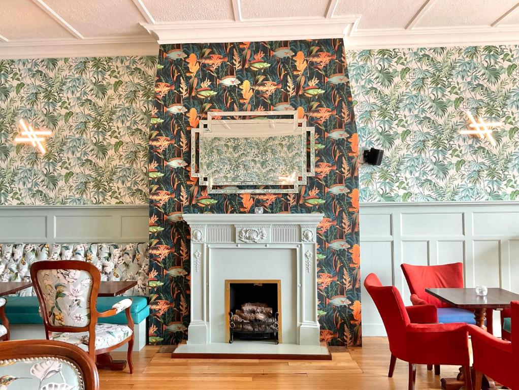 uma sala de estar com lareira e papel de parede floral em Ashton Court Hotel em Exmouth