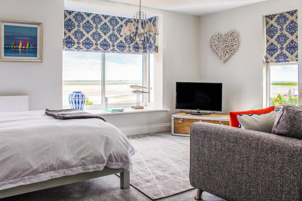 Seafront Apartment with Stunning Views في كْليثوربس: غرفة نوم بسرير وتلفزيون وأريكة