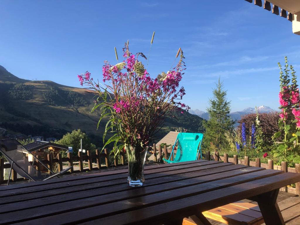 Appartement avec terrasse magnifique vue montagne في سانت فرانسوا-لونغشامب: إناء من الزهور على طاولة خشبية