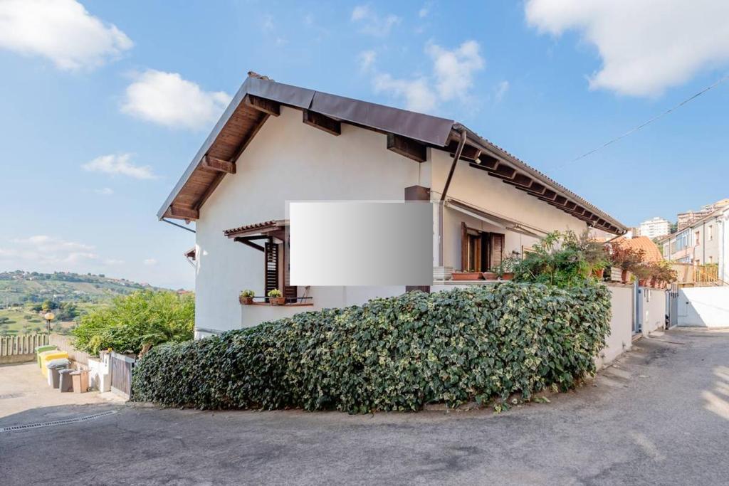 une maison blanche avec un grand bush devant elle dans l'établissement Casa Francesca quiete e cortesia - Via San Camillo de Lellis, 56 Chieti-, à Chieti