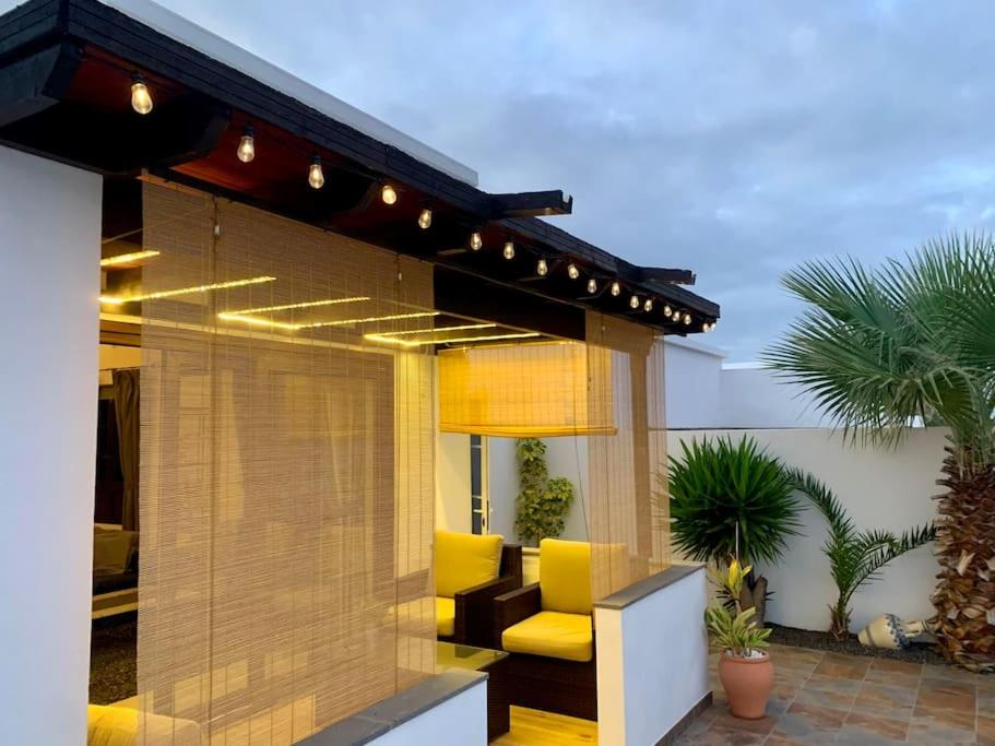 a patio with a yellow couch in a house at La Mar Poolvilla in Costa Teguise