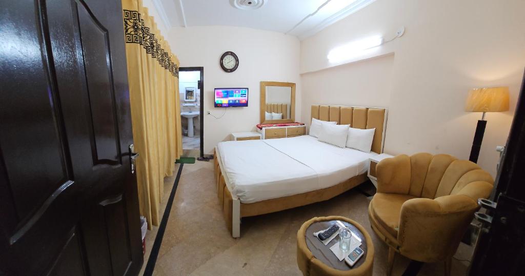 um quarto de hotel com uma cama e uma cadeira em Frank in guest house em Islamabad