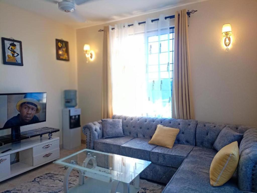 a living room with a blue couch and a tv at Inviting 1-Bed Cozy Apartment in Mombasa in Mombasa