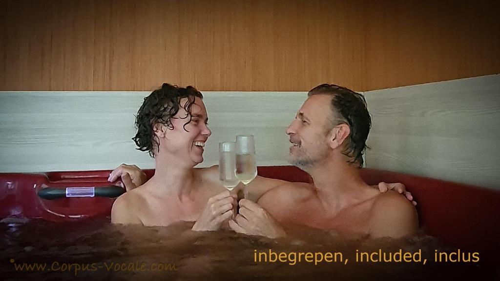 dos hombres en una bañera con una copa de vino en B&B CountryHeART en Sint-Laureins