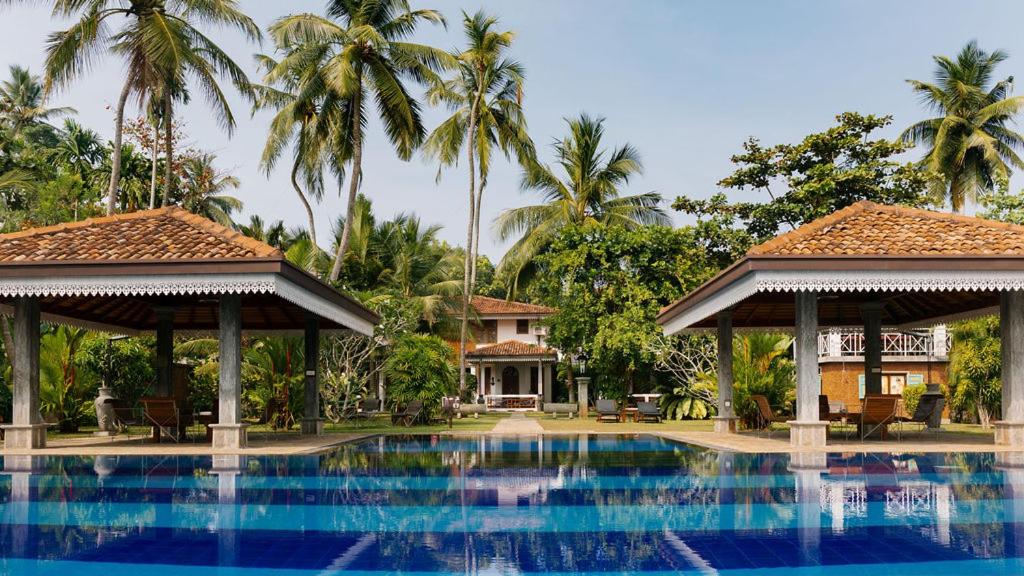 una piscina frente a una casa con palmeras en AMAL VILLA, en Bentota
