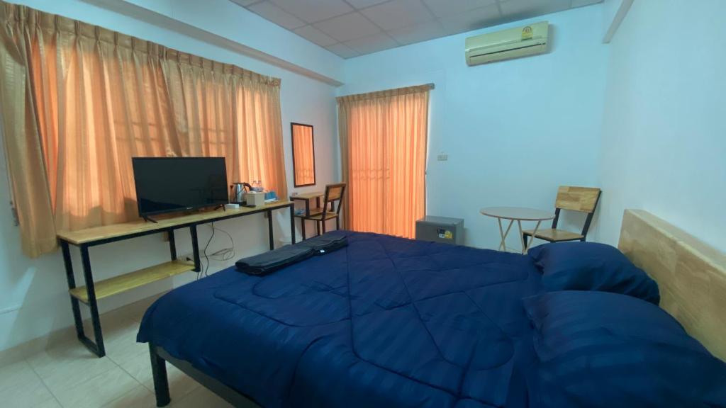 a bedroom with a blue bed and a desk and chairs at ธนทรัพย์อพาร์ทเม้นท์ Room01 in Pathum Thani