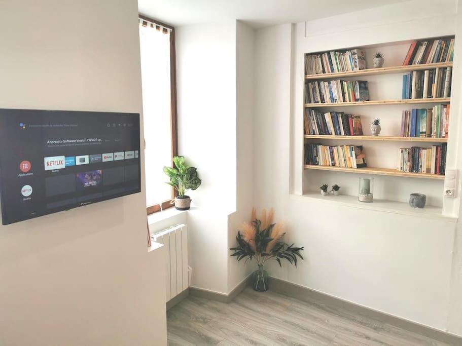 a living room with a tv and a book shelf at Charmant Studio idéalement situé in Morez