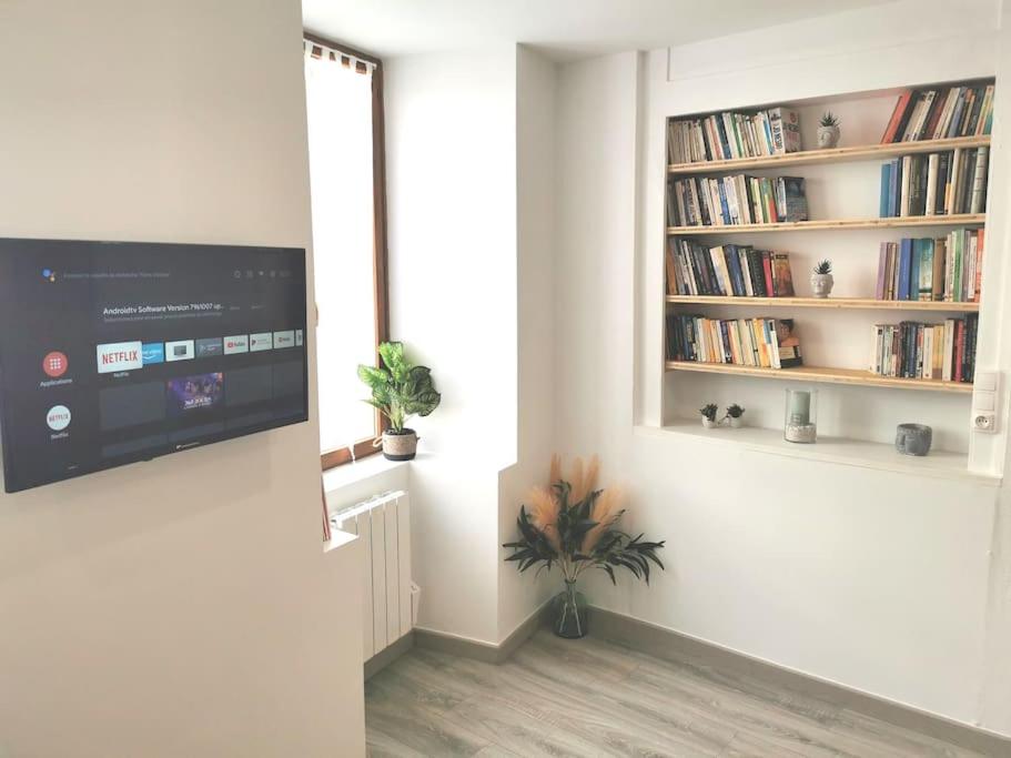 ein Wohnzimmer mit einem TV und einem Bücherregal in der Unterkunft Charmant Studio idéalement situé in Morez