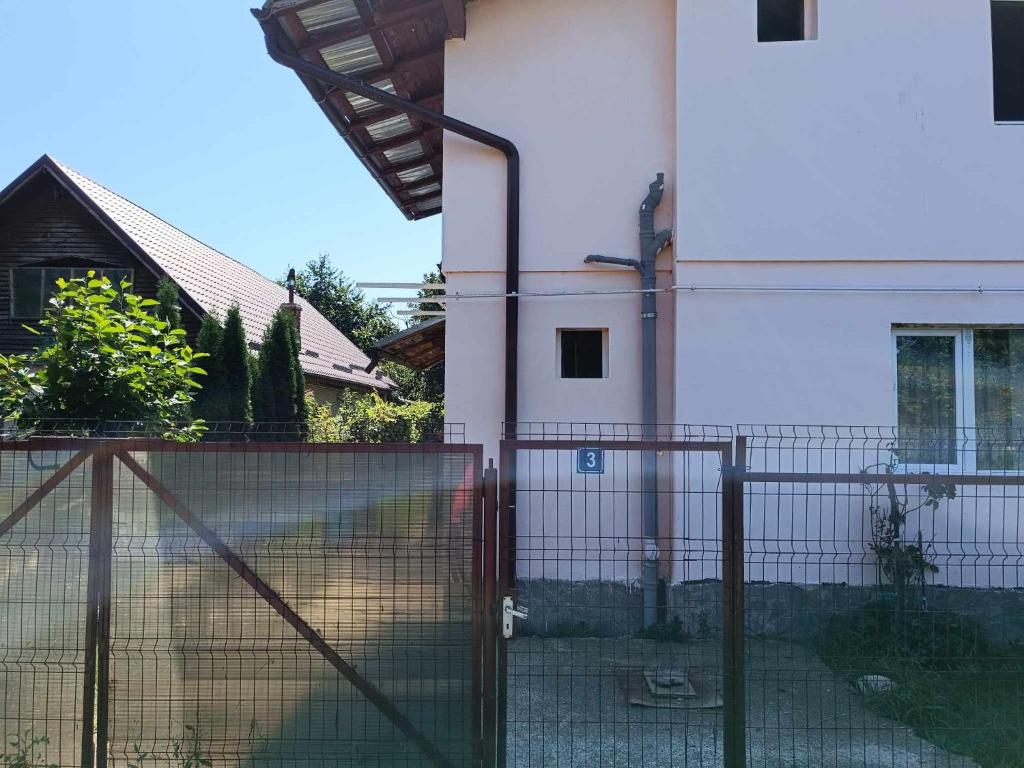 a fence in front of a house with a building at Casa Marieta in Breaza de Sus