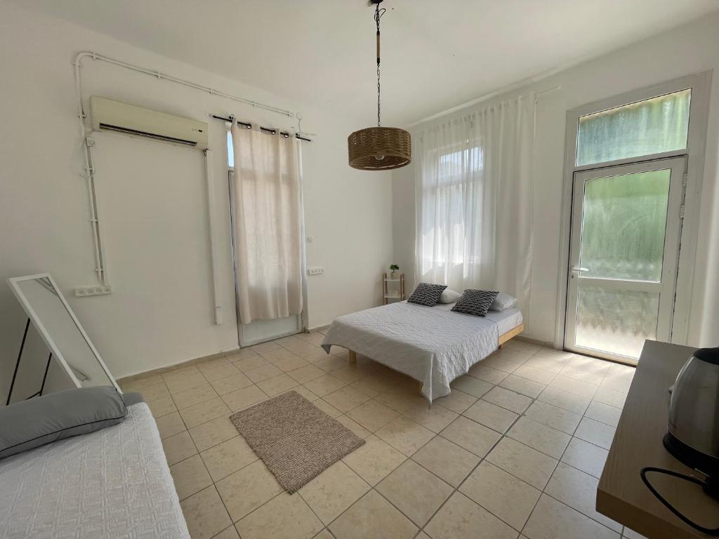 a white room with a bed and a window at Godson Apartment in Haifa