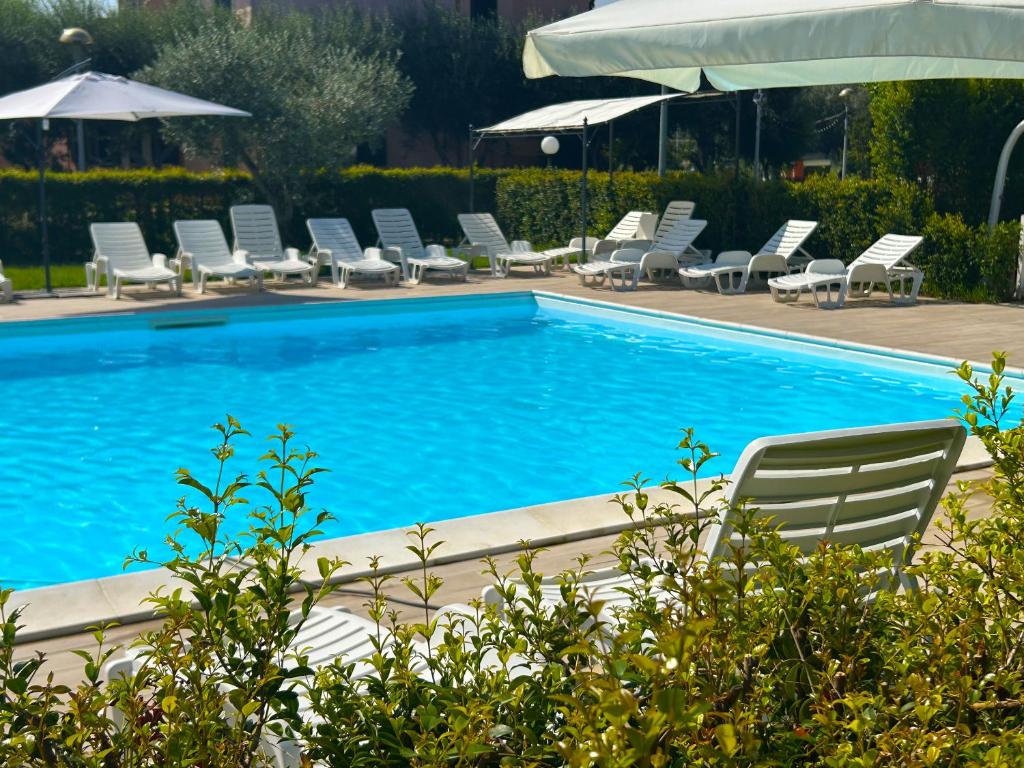 a swimming pool with chairs and umbrellas at Resort Park Village in Rossano