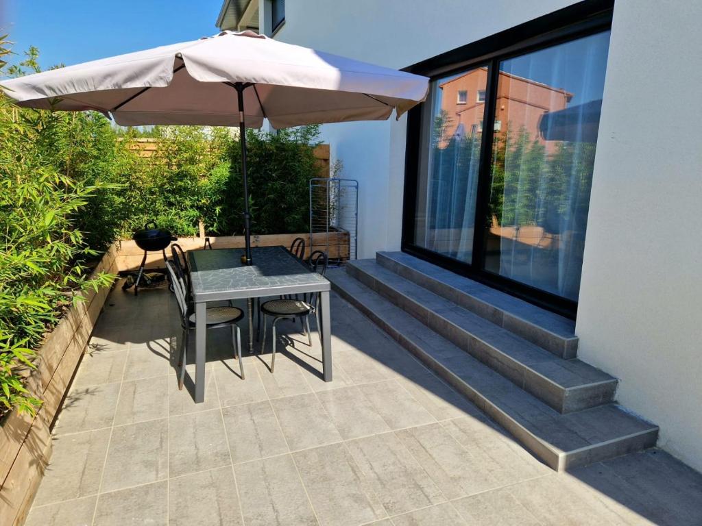 un patio con mesa y sombrilla en Appart moderne avec jardin à 5min de la plage, en Sainte-Marie-la-Mer