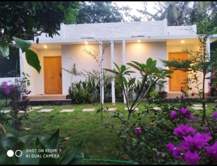 a small white house with flowers in front of it at Cemare Cottage in Lembar