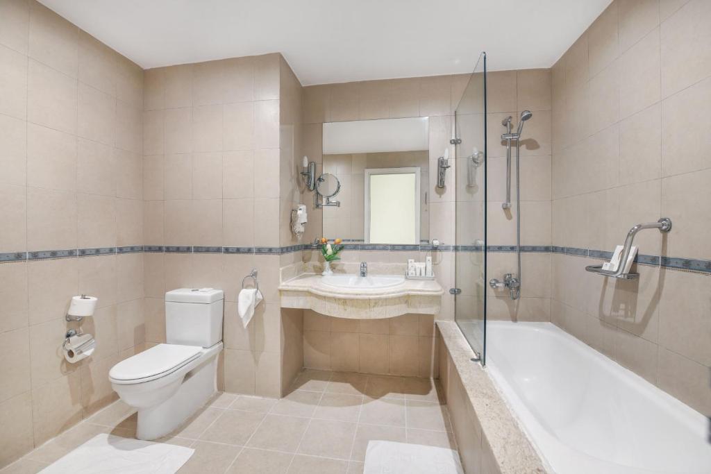 a bathroom with a toilet and a tub and a sink at Tolip Aswan Hotel in Aswan