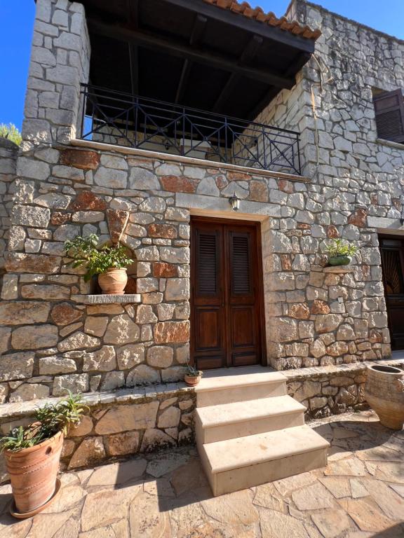 a stone building with a wooden door and stairs at Gloria Holiday Homes Apartments in Lithakia