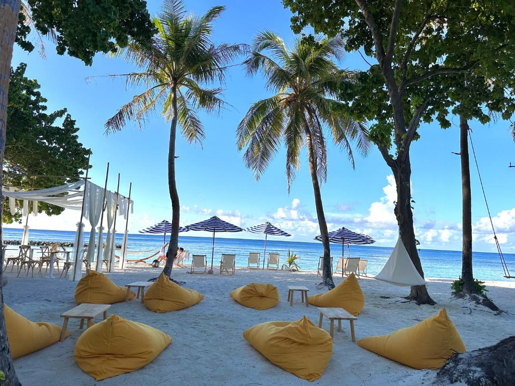 a sandy beach with chairs and umbrellas and the ocean at Galaxy Sunrise Sea View in Fulidhoo