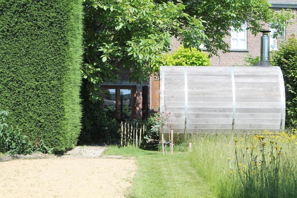 un jardín con una gran pared blanca junto a un edificio en Maison Raymond - Vakantiehuisje met houtgestookte sauna, 