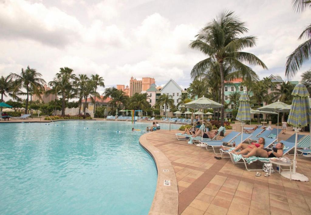 a pool at a resort with people sitting in chairs at Harbourside Resort, Paradise Island Bahamas in Nassau
