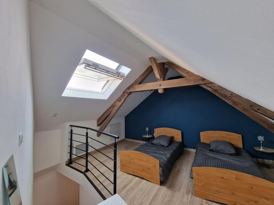 - 2 lits dans une chambre avec un mur bleu dans l'établissement Maison chaleureuse, centre bourg, à Casson