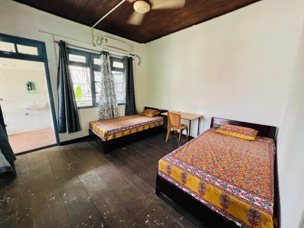 a room with two beds and a table and a window at Levi Home Guest House & Retreat Centre in Siliguri