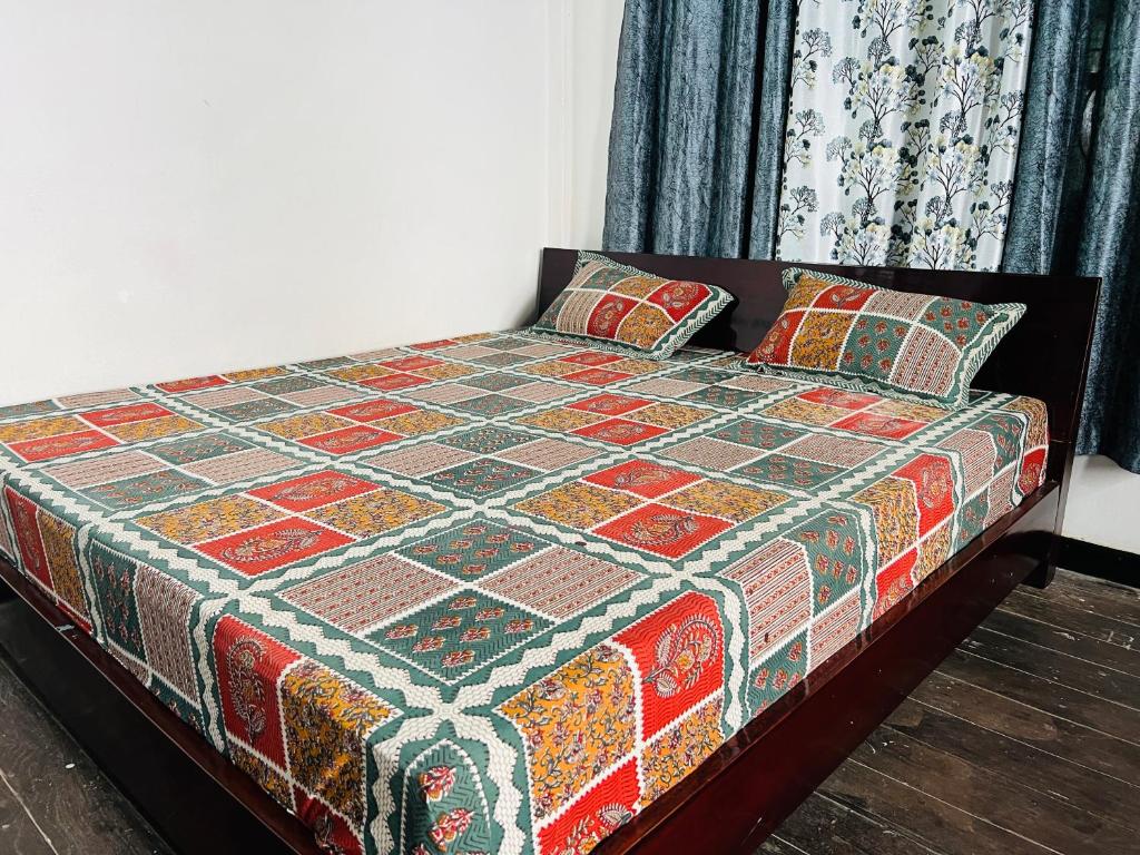a bed with a colorful blanket and pillows on it at Levi Home Guest House & Retreat Centre in Siliguri