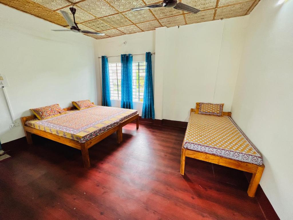 a room with two beds and a window with blue curtains at Levi Home Guest House & Retreat Centre in Siliguri