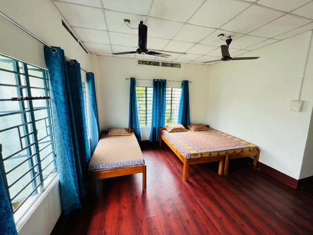 a room with two beds and a window at Levi Home Guest House & Retreat Centre in Siliguri