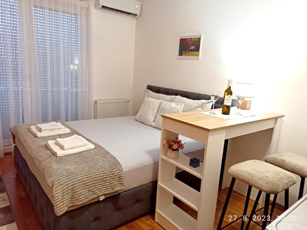 a bedroom with a bed and a table with a bottle of wine at Studio Apartman TIM in Doboj