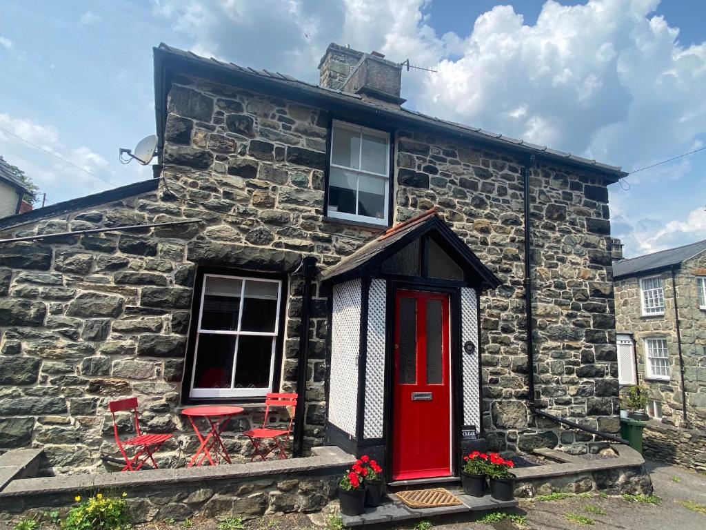 a stone house with a red door and red chairs at Cottage in heart of Dolgellau with parking in Dolgellau