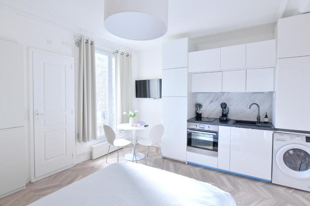 uma cozinha branca com uma mesa e uma máquina de lavar roupa em Studio 1 Pièce 20 m2 em Paris