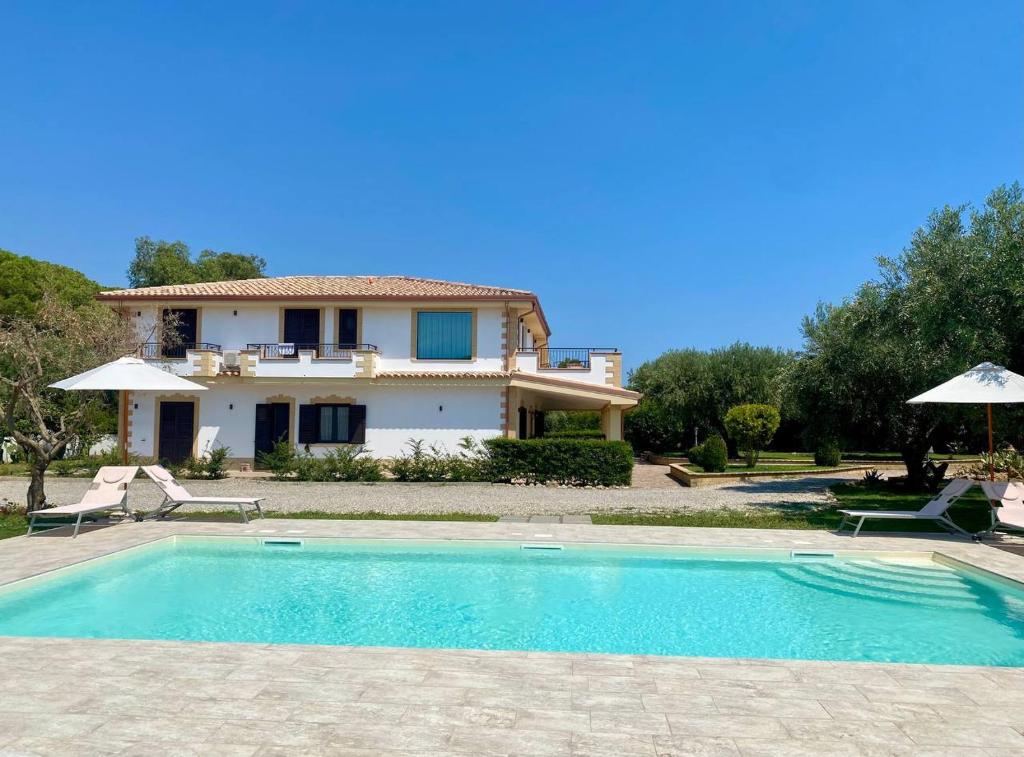 eine Villa mit einem Pool vor einem Haus in der Unterkunft Relais Ruggiero in Le Castella