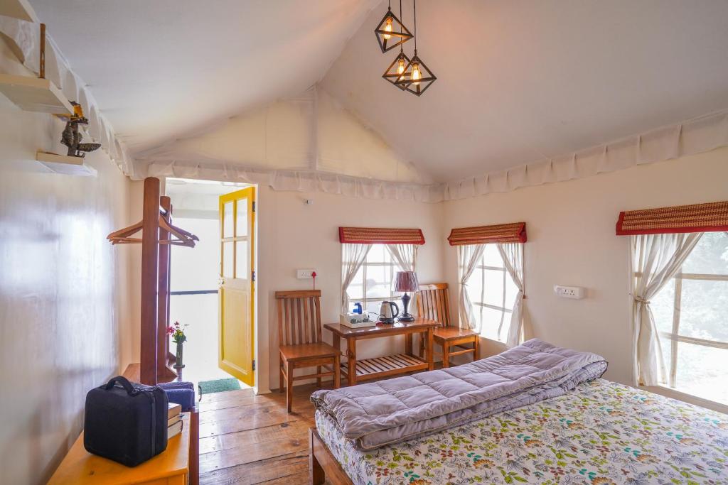 - une chambre avec un lit, un bureau et des fenêtres dans l'établissement Moksham Himalayan Campsite Pangot, à Nainital