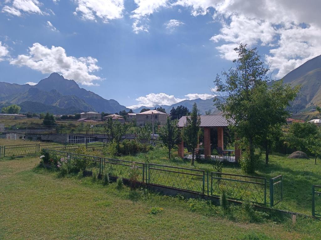 Ein Zaun auf einem Feld mit Bergen im Hintergrund in der Unterkunft Kamara Guest House in Kazbegi