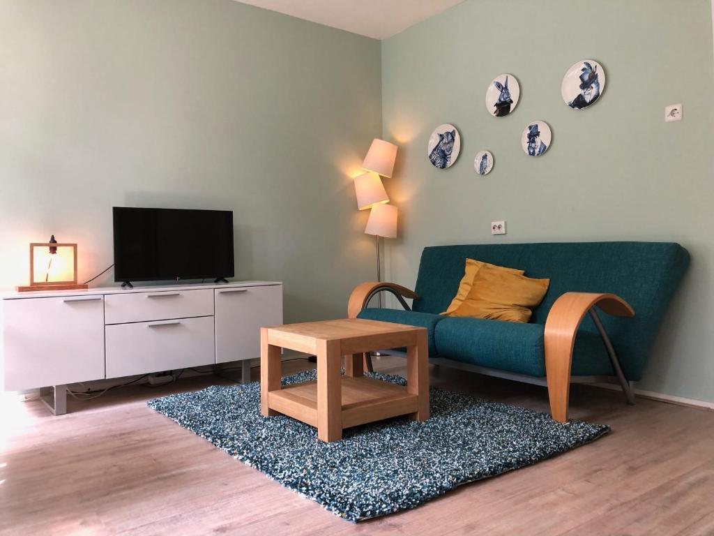 ein Wohnzimmer mit einem grünen Sofa und einem Tisch in der Unterkunft Veluwe Nature Home - 2 persons in Otterlo