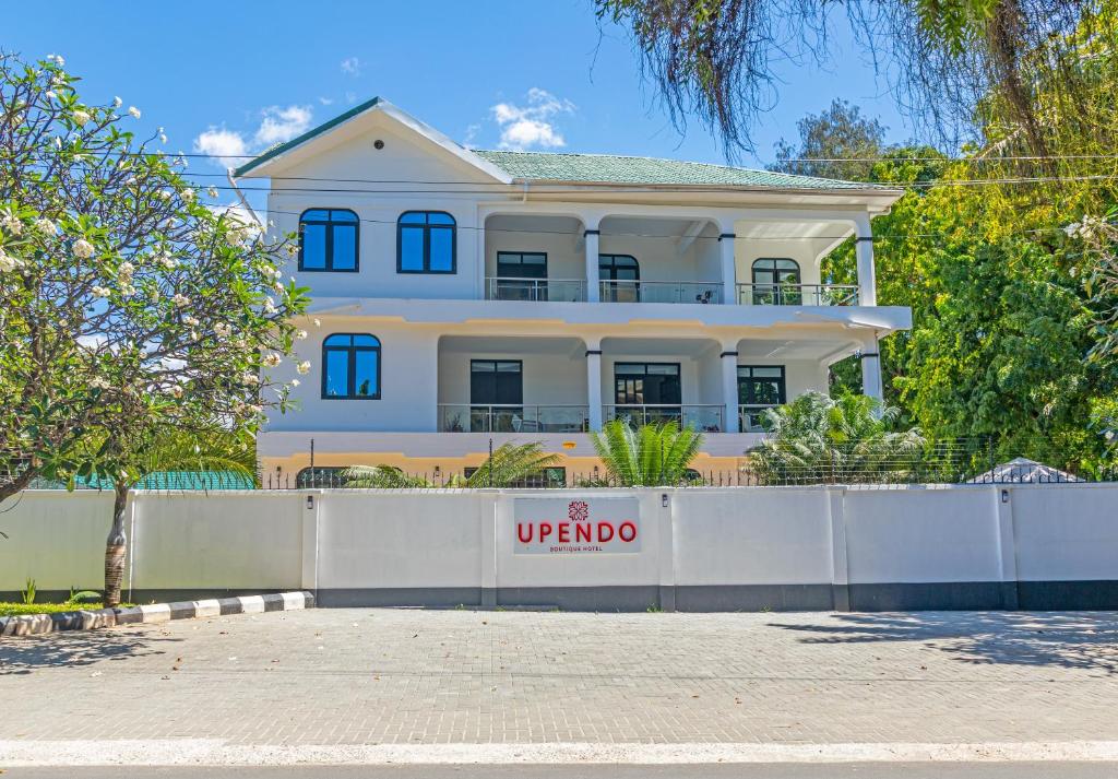 a large white house behind a white fence at Upendo Boutique Hotel, Dar es Salaam in Dar es Salaam