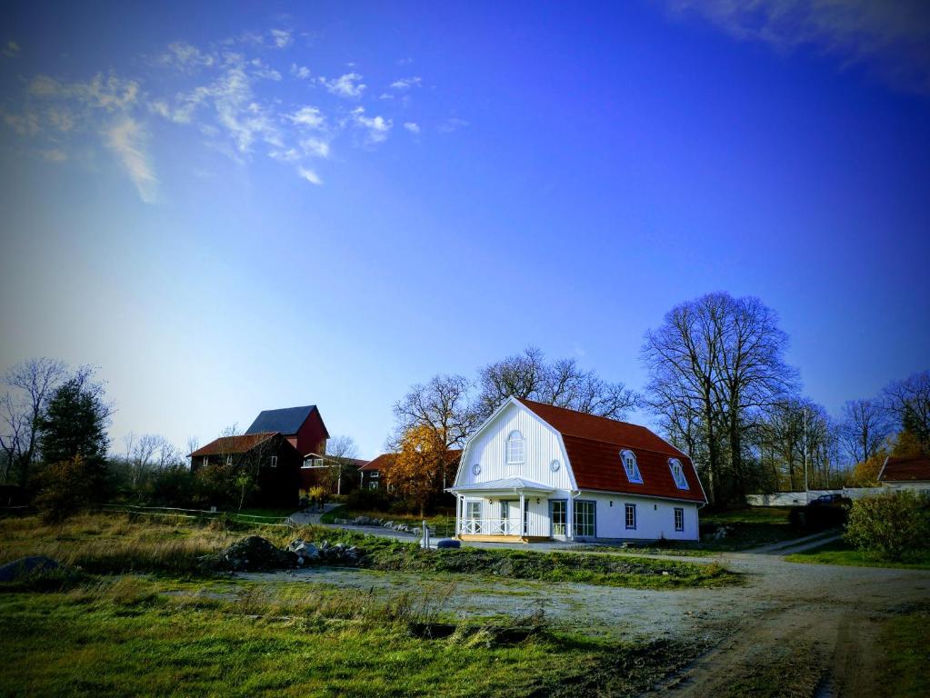 een wit huis met een rood dak in een veld bij Jädra Gårdshotel in Enköping
