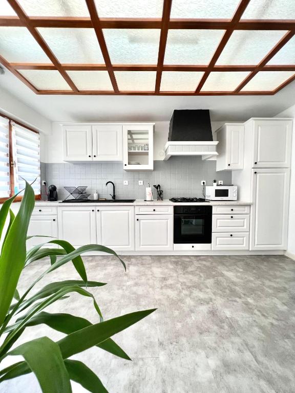 une cuisine avec des placards blancs et un plafond dans l'établissement La Verrière d'Opale - Maison proche plage et CNPE EDF, à Grand-Fort-Philippe