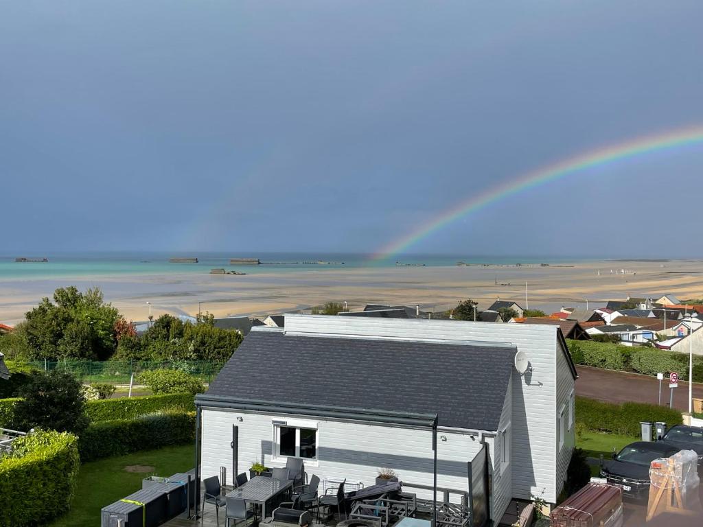 ein Regenbogen über einem weißen Gebäude mit einem Haus in der Unterkunft Plage du Débarquement. Maison bord de Mer in Saint-Côme-de-Fresné