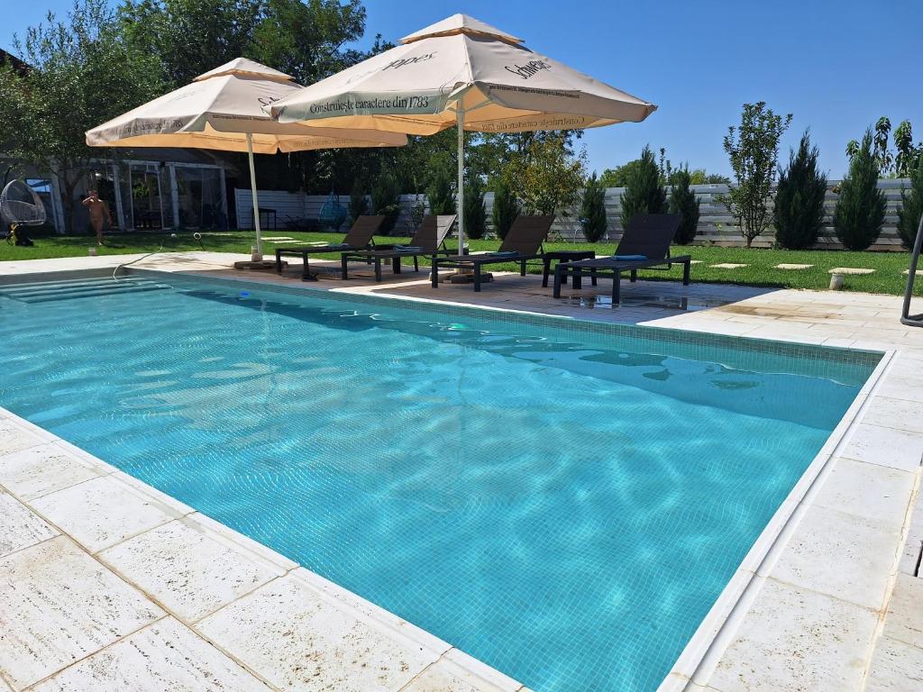 een zwembad met twee parasols en twee stoelen bij Modern 3 bedroom house with a private pool in Popeşti-Leordeni