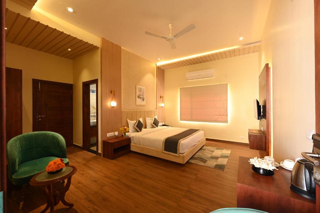 a hotel room with a bed and a green chair at THE GANGA RESORT in Bikaner