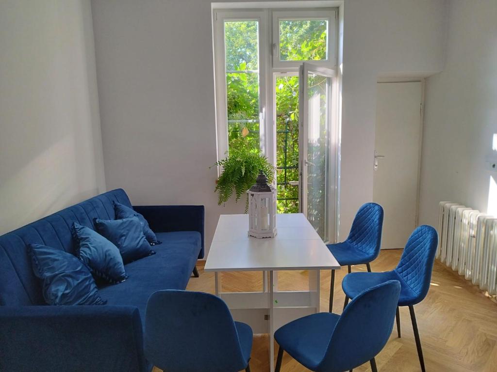 uma sala de estar com um sofá azul e cadeiras azuis em Urban Nest Apartments Brodowicza 14 em Cracóvia