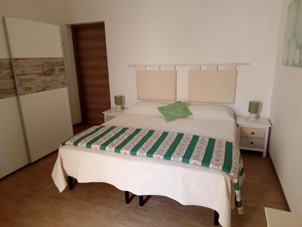 1 dormitorio con cama blanca y almohada verde en Affittacamere da Claudio&Kevin con uso cucina, en Posada